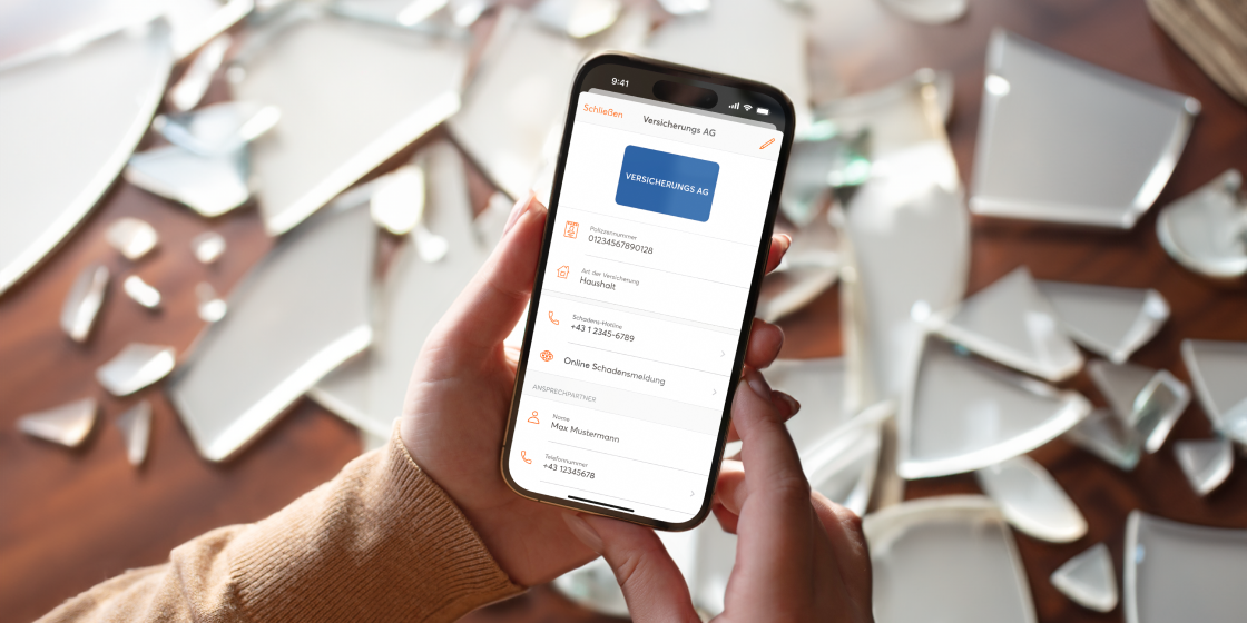 Smartphone, auf dem die Versicherungsdaten in mobile-pocket gesichert sind. Dahinter sind Scherben zu sehen.