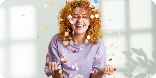 Frau, die sich über einen bunten Konfetti-Regen freut